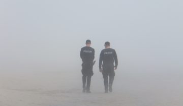 2 police officers walking in a grey haze